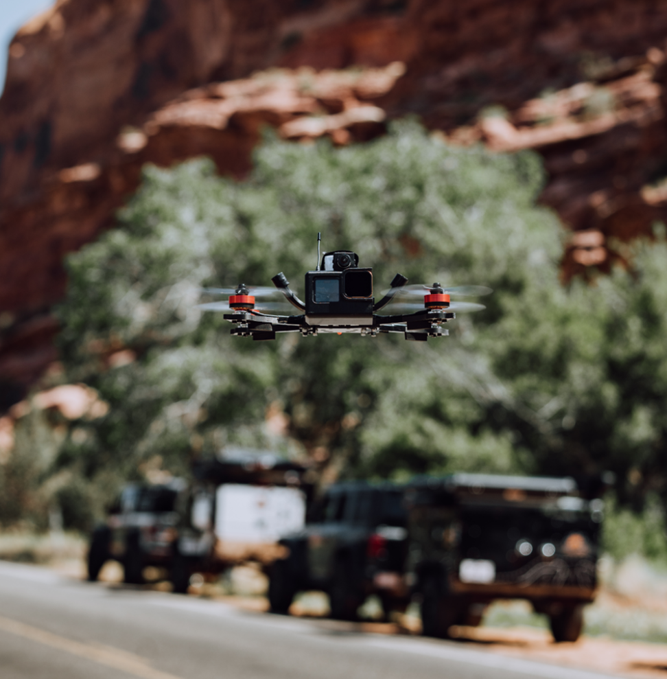 Close of a Go Pro camera on a flying drone in front of a desert canyon valley background in front of a giant tree